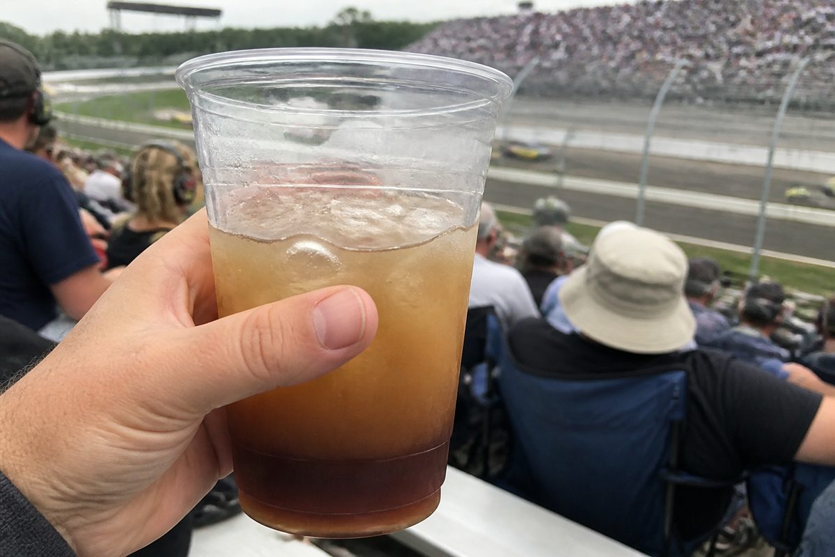 Plastic cup containing a brown mixed drink with melting ice