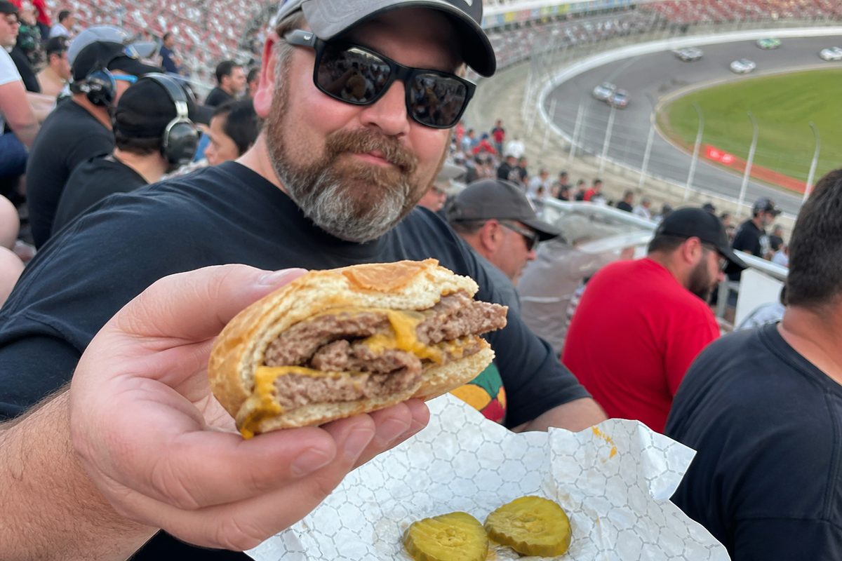Race fan offering a partially eaten cheeseburger